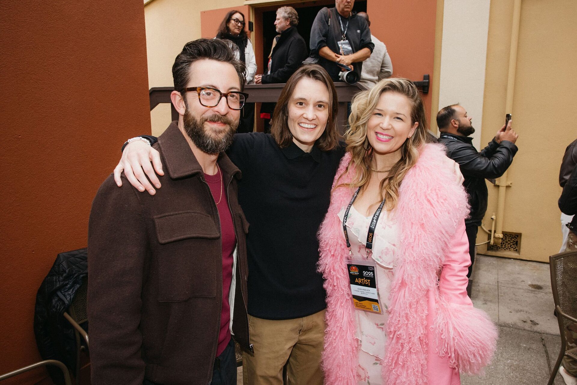 Three people standing together and smiling at a StreamFest event